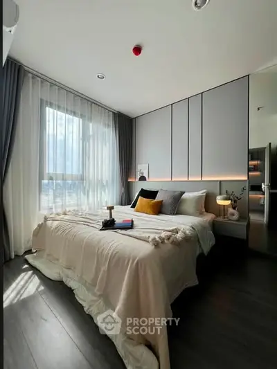 Modern bedroom with elegant decor, large window, and cozy ambiance in a stylish apartment.