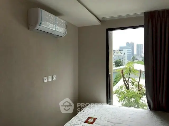 Modern bedroom with city view and air conditioning in urban apartment.