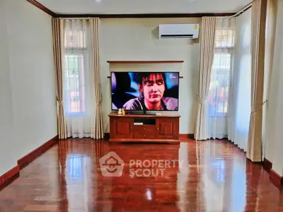Spacious living room with wooden floors and modern entertainment setup.