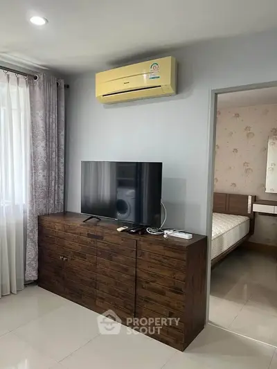 Modern living room with air conditioning and stylish wooden cabinet under a flat-screen TV.