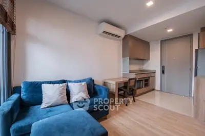 Modern living room with blue sofa and compact kitchen in open layout apartment.