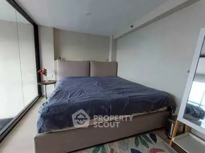 Spacious bedroom with large window and modern decor in a stylish apartment.