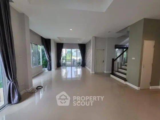 Spacious living room with large windows and elegant staircase in modern home