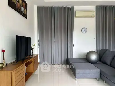 Modern living room with sleek gray sofa, wall-mounted TV, and air conditioning unit, perfect for relaxation.