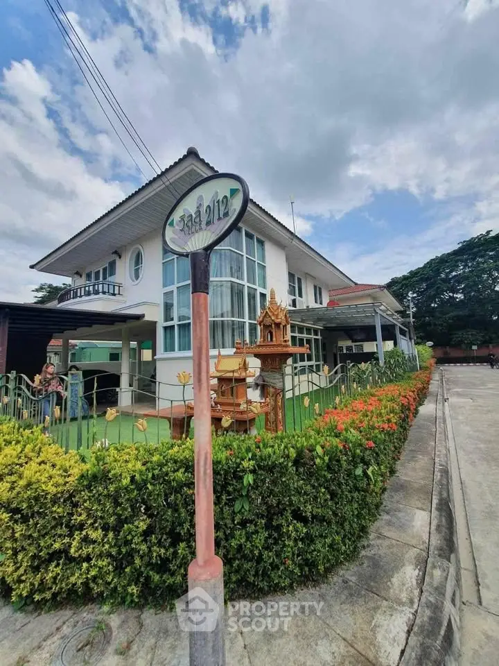 Charming two-story house with lush garden and traditional decor on a corner lot.