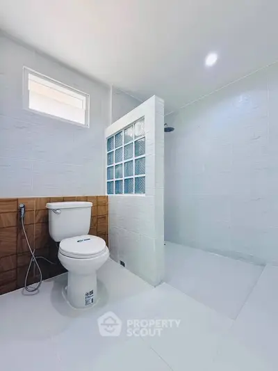 Spacious modern bathroom with sleek white tiles and glass partition shower.