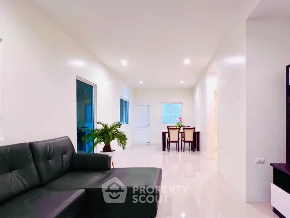 Spacious modern living room with sleek black sofa and elegant dining area.