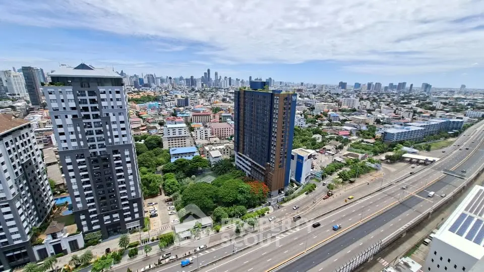 Stunning cityscape view from high-rise apartment with modern buildings and highway access.