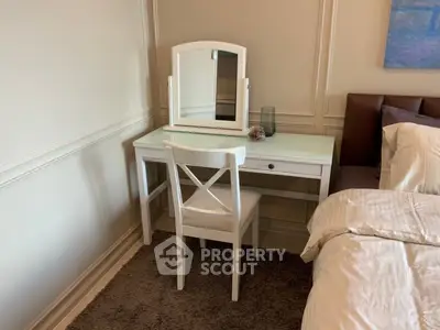 Cozy bedroom corner with elegant white vanity and chair beside a plush bed, perfect for relaxation.