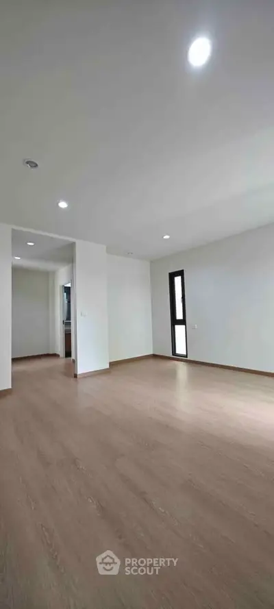 Spacious empty living room with wooden flooring and recessed lighting