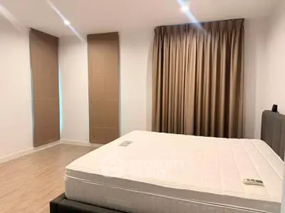 Spacious bedroom with large windows and elegant curtains in modern apartment.