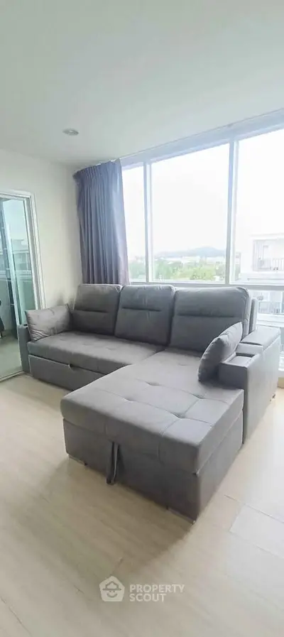 Spacious living room with modern gray sectional sofa and large windows offering natural light.