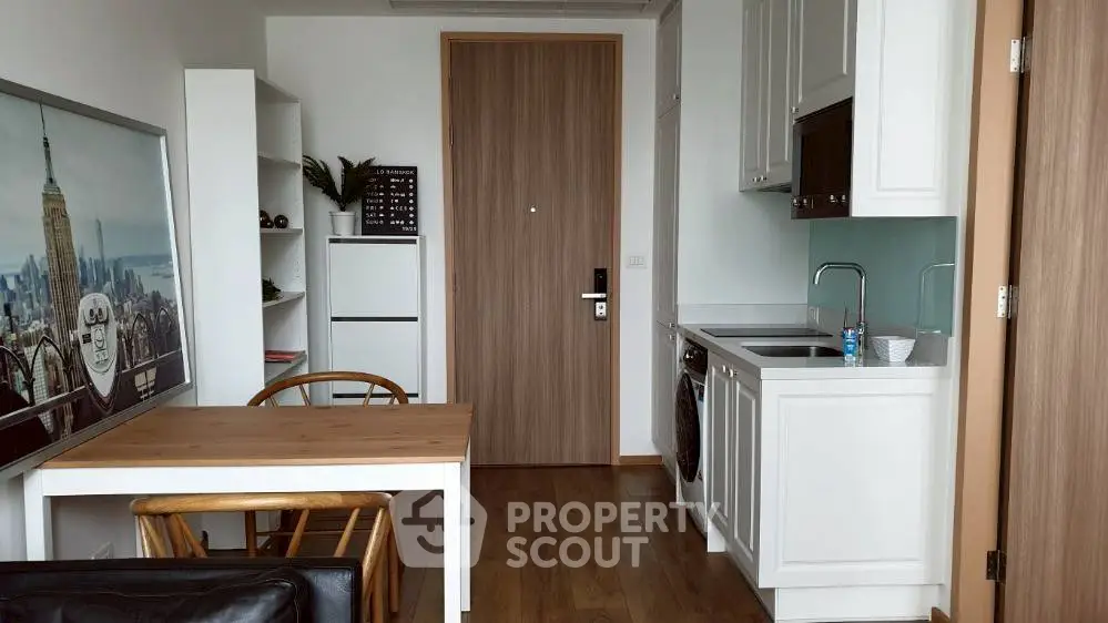 Modern kitchen with wooden dining table and sleek cabinetry in a cozy apartment setting.