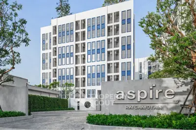 Modern apartment building with sleek design and lush greenery at Aspire Ratchayothin.