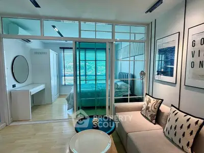 Modern studio apartment with glass partition, cozy living area, and stylish decor.
