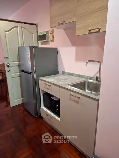 Compact kitchen with modern appliances and sleek cabinetry in cozy apartment.