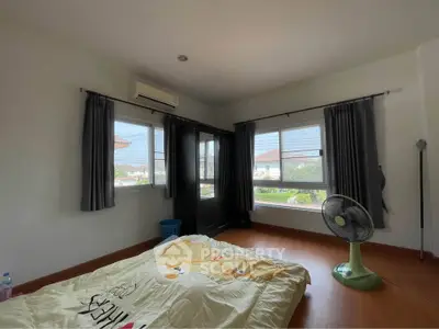 Spacious bedroom with large windows and natural light, featuring a cozy bed and modern decor.