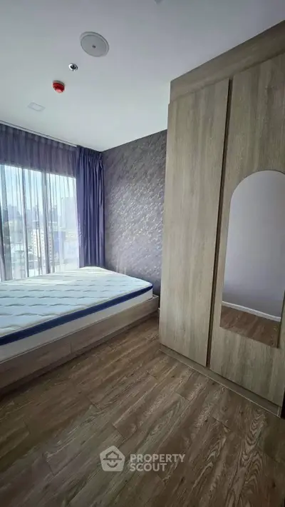 Modern bedroom with large window and wooden wardrobe in stylish apartment
