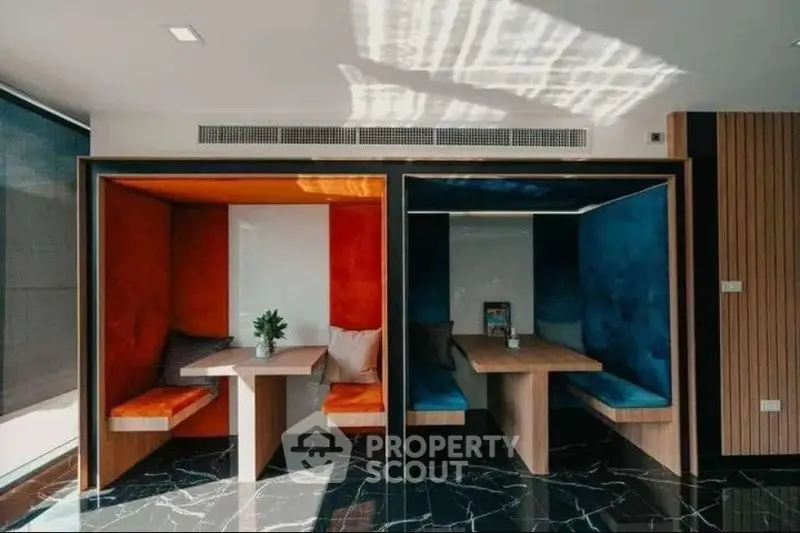 Modern co-working space with vibrant seating booths and sleek marble flooring.