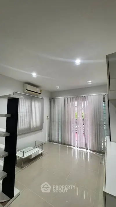 Modern living room with sleek design, air conditioning, and natural light through large windows.