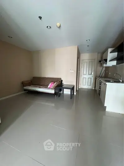 Spacious living room with modern kitchenette and cozy sofa in a stylish apartment.