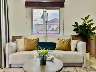 Cozy living room with stylish sofa, cushions, and indoor plant, perfect for relaxation and comfort.