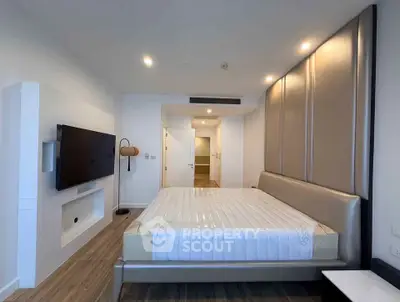 Modern bedroom with sleek design and mounted TV, featuring a stylish bed and contemporary lighting.