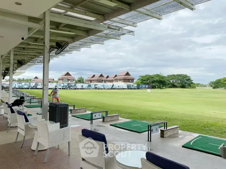 Luxurious golf course view from modern clubhouse with seating area and lush green landscape.