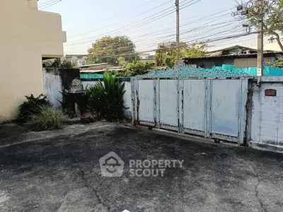 Spacious residential driveway with secure gated entrance and lush greenery.