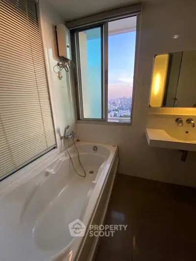 Luxurious bathroom with bathtub and stunning city view through large window.