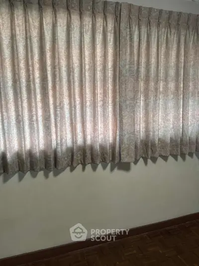 Cozy room with elegant curtains and wooden flooring, perfect for a serene living space.