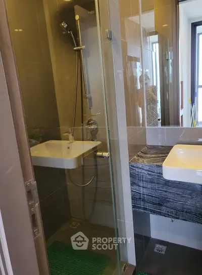 Modern bathroom with glass shower and stylish sink in contemporary apartment