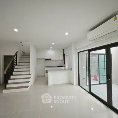 Modern open-plan living space with sleek kitchen and staircase