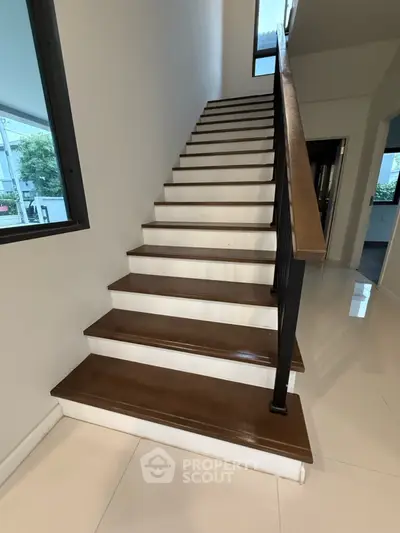 Elegant wooden staircase with sleek black railing in modern home interior