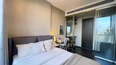 Modern bedroom with sleek design and city view, featuring a cozy bed and stylish workspace.