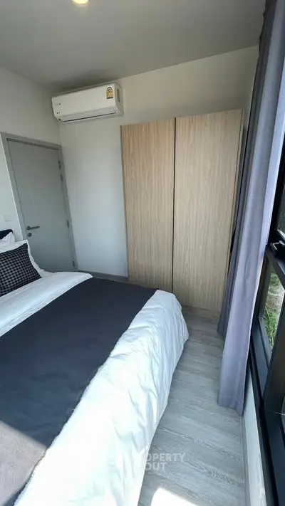 Modern bedroom with sleek design, featuring a comfortable bed, stylish wardrobe, and natural light from large window.