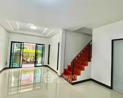 Spacious modern living room with glossy floors and staircase, leading to a balcony with garden view.