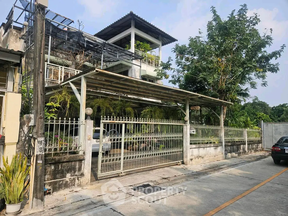 Charming multi-story home with lush greenery and gated entrance in a serene neighborhood.