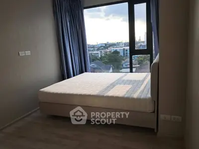 Modern bedroom with large window offering city view, featuring a comfortable bed and elegant curtains.