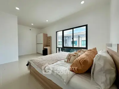 Spacious bedroom with modern decor and large window offering natural light.