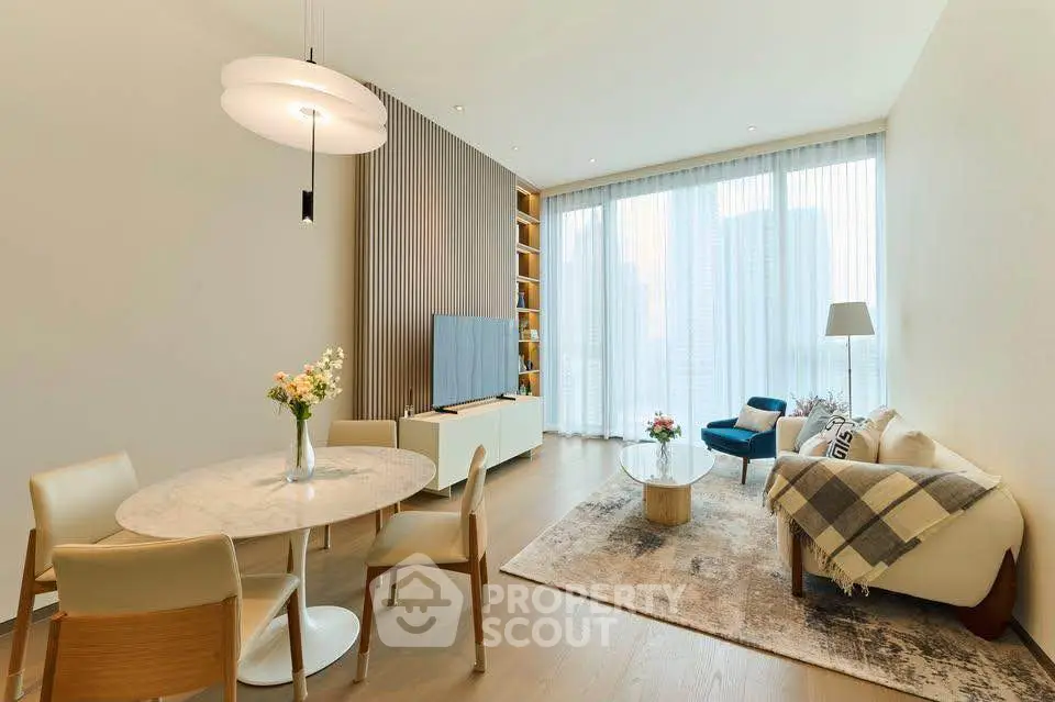Elegant living room with modern decor, large windows, and stylish furniture in a high-rise apartment.