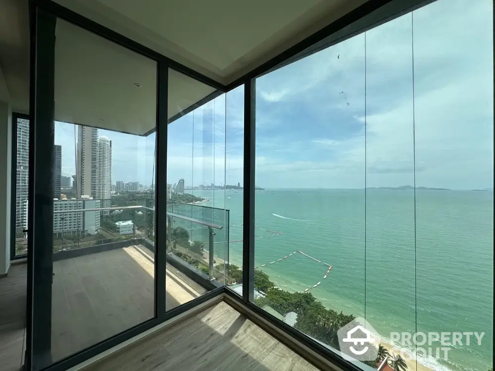 Stunning ocean view from modern high-rise apartment with floor-to-ceiling windows.