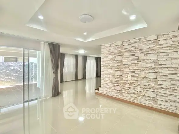 Spacious modern living room with stone accent wall and large windows