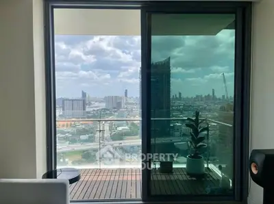 Stunning city view from modern balcony with glass doors and cozy seating area.