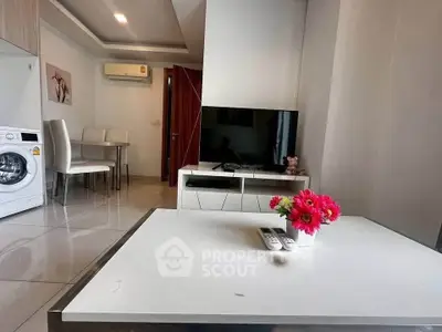 Modern living room with TV, washing machine, and dining area in a stylish apartment.