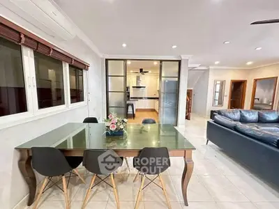 Spacious open-plan living and dining area with modern furnishings and glass dining table.