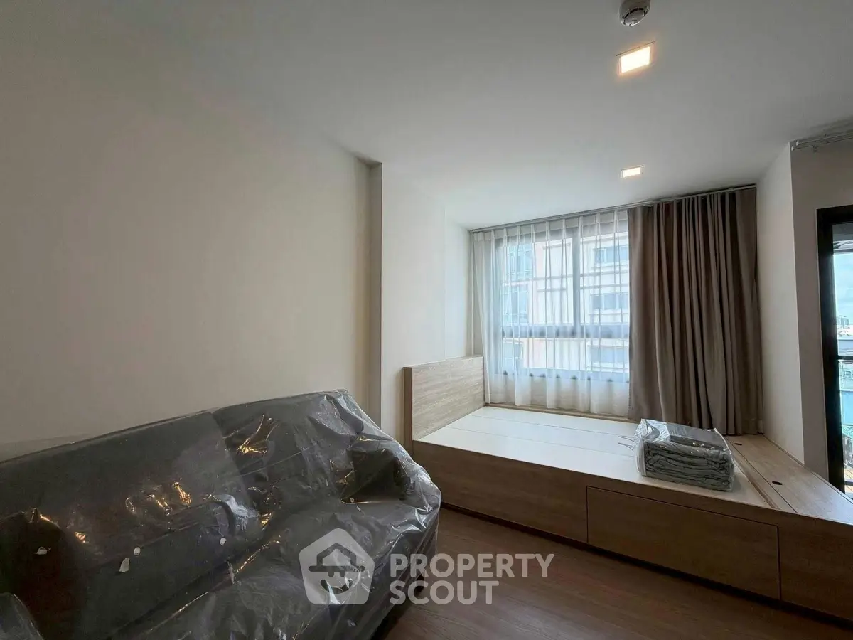 Modern bedroom with large window and cozy sofa, perfect for relaxation.