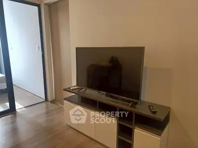 Modern living room with sleek TV stand and flat-screen TV, wooden flooring, and minimalist design.
