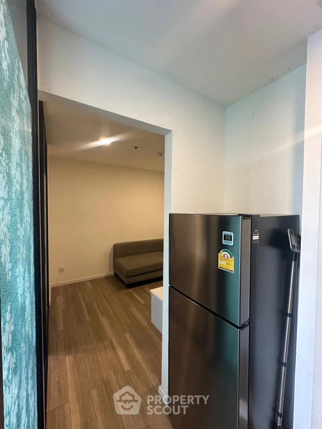 Modern apartment interior with sleek fridge and cozy living area, perfect for urban living.