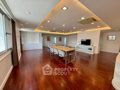 Spacious open-plan living room with elegant wooden flooring and modern lighting.